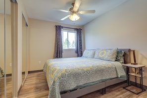 A bedroom with a bed, a nightstand, a ceiling fan, a window with curtains, and a wooden floor. - 3 Mi to Main St & Riverwalk Trail! Cañon City Apt (Cañon City)