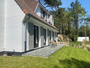 A two-story house with a white exterior, a tiled roof, and a covered porch with chairs. - Villa Hardelot, near the golf course and the beach (Neufchâtel-Hardelot)