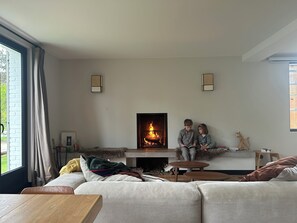 A living room with a fireplace, a sofa, a coffee table, and a window.