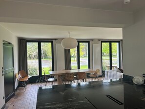 A modern dining area with a large table and chairs, large windows with curtains, and a hanging light fixture. - Villa Hardelot, near the golf course and the beach (Neufchâtel-Hardelot)
