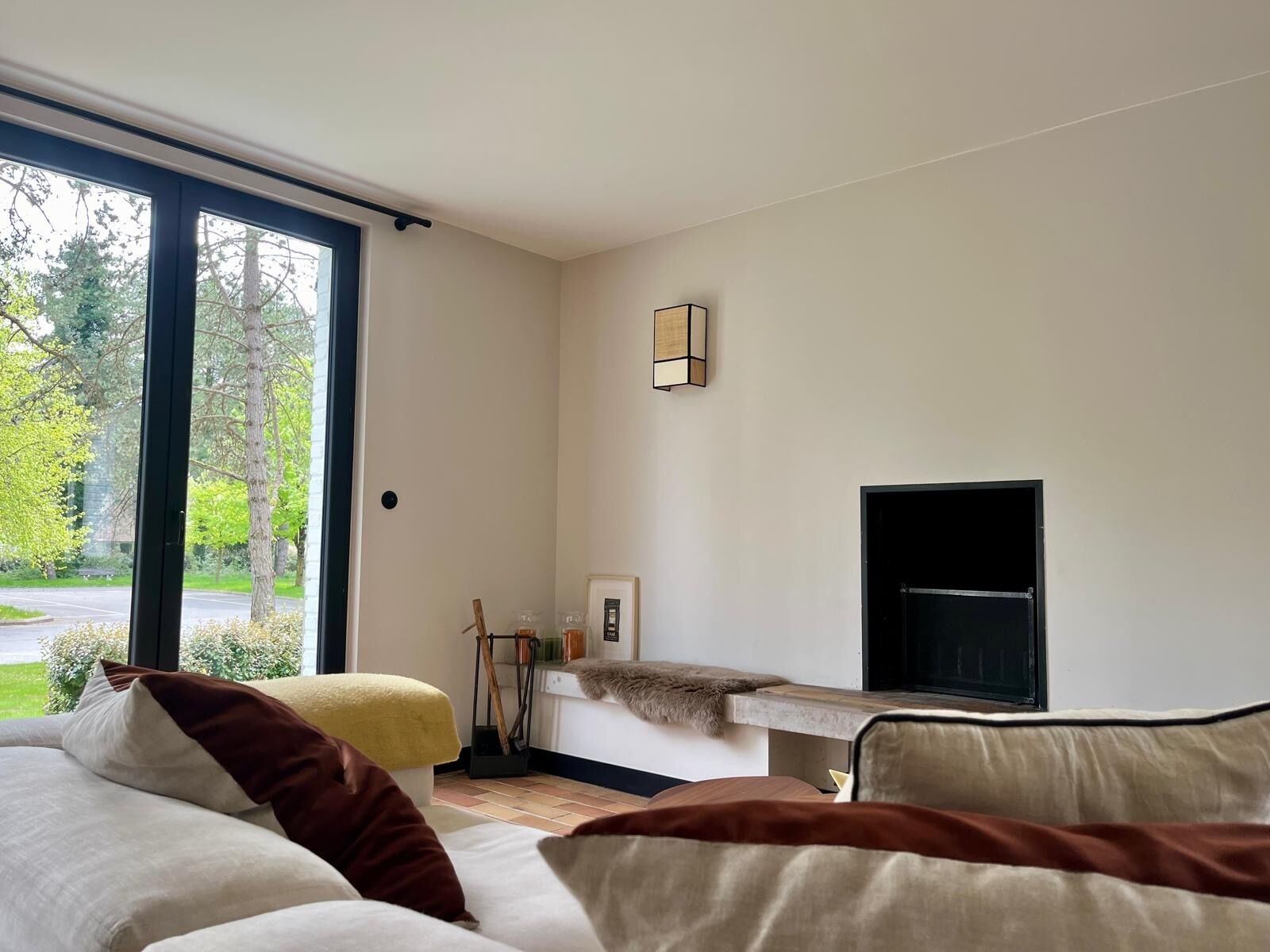 A modern living room with a large window, a fireplace, and a cozy seating area.