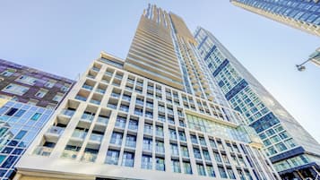 A high-rise building with a modern architectural design, featuring a prominent glass facade and multiple balconies.