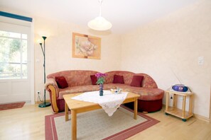 En stue med en sofa, et træ sofabord, en gulvlampe, et billede og en radio på et natbord.