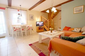 Ein gemütliches Wohnzimmer mit Essbereich, Treppe und Fernseher.