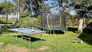 Ein Außenbereich mit Tischtennisplatte und Trampolin.