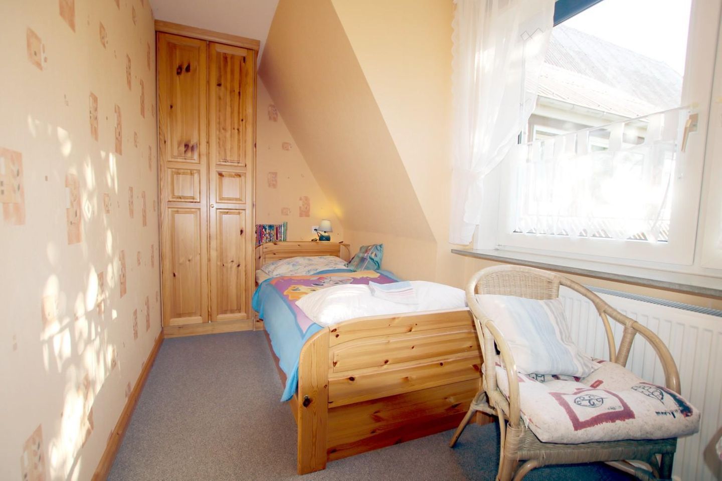 Um quarto com uma cama de madeira, uma cadeira, uma janela com cortinas e um guarda-roupa.