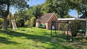 Een woonhuis met een bakstenen gevel, een schommel en een overdekt terras.