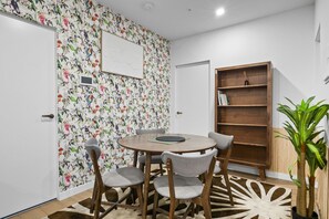 A room with a round table, four chairs, a bookshelf, and a floral wallpaper. - High-Rise 2-Bed Apt at Trio Boxhill with Car Park (Box Hill)