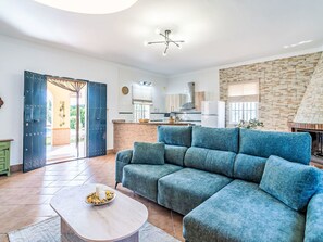Ein modernes Wohnzimmer mit einer Eckcouch, einem Couchtisch und einer Küche im Hintergrund.