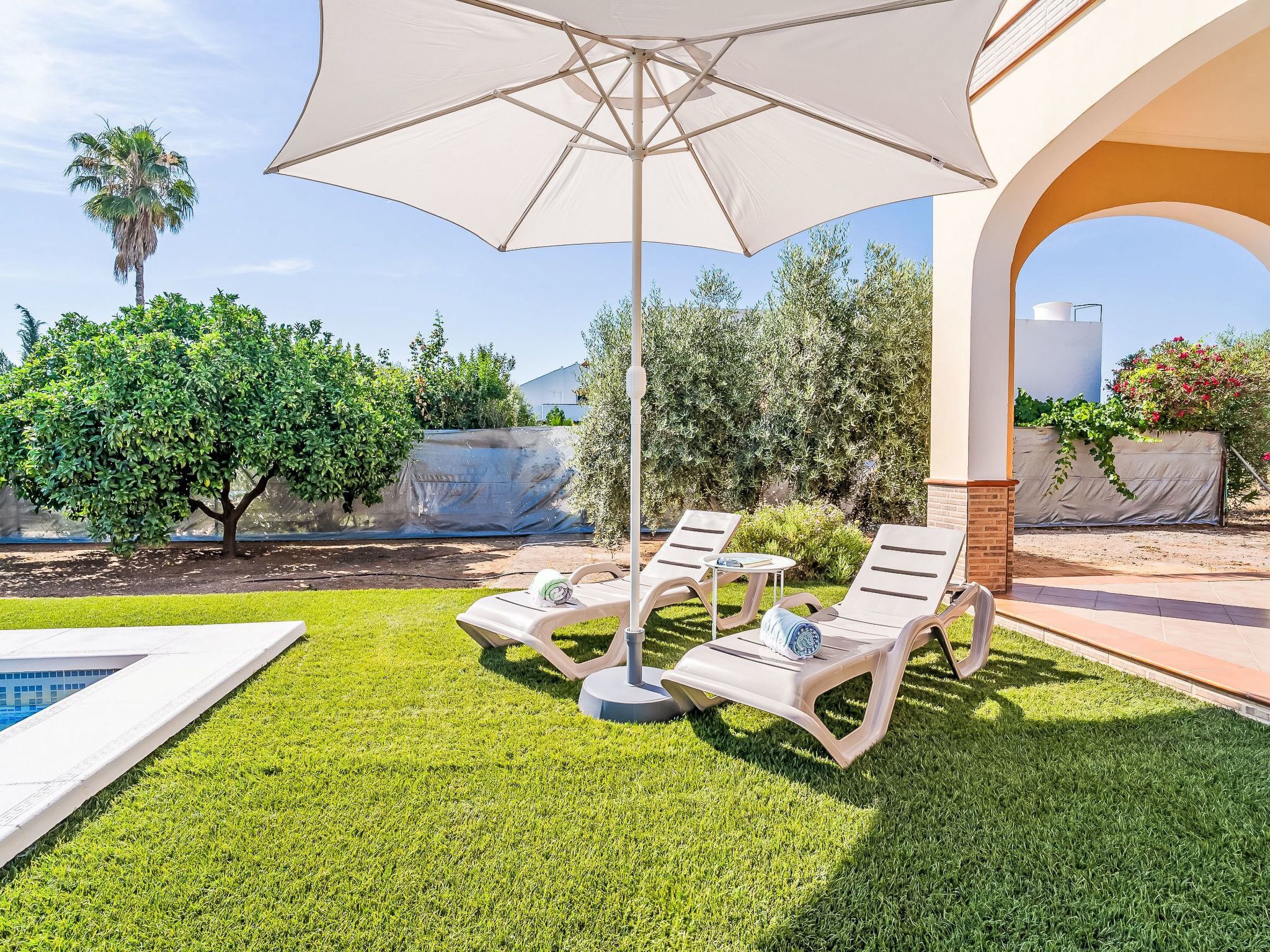 Uma área à beira da piscina com um espaço de estar coberto, piscina e vista para a paisagem ao redor.