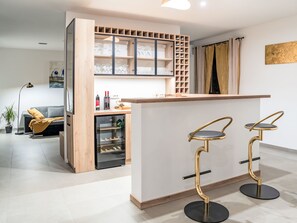 A modern kitchen with a built-in wine rack, a refrigerator, and two bar stools. - Dominika by Interhome (Motovun)
