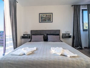 A bedroom with a bed, two bedside tables, a painting, and a window with curtains. - Dominika by Interhome (Motovun)