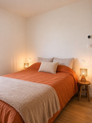 Ein Schlafzimmer mit einem großen Bett, zwei Nachttischlampen und einem Thermostat an der Wand.