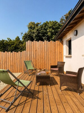 Eine Terrasse im Freien mit Holzlattenzaun, Korbmöbeln und einem Tisch mit Getränken.