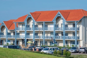 A multi-story hotel with red roofs and blue balconies. - Seaside Retreat near the Casino (Biscarrosse)