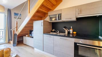 Uma cozinha moderna com micro-ondas embutido, forno e escada de madeira.
