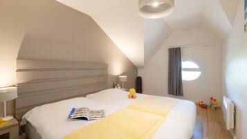 A bedroom with a large bed, a bedside lamp, a window with curtains, and a ceiling light fixture.