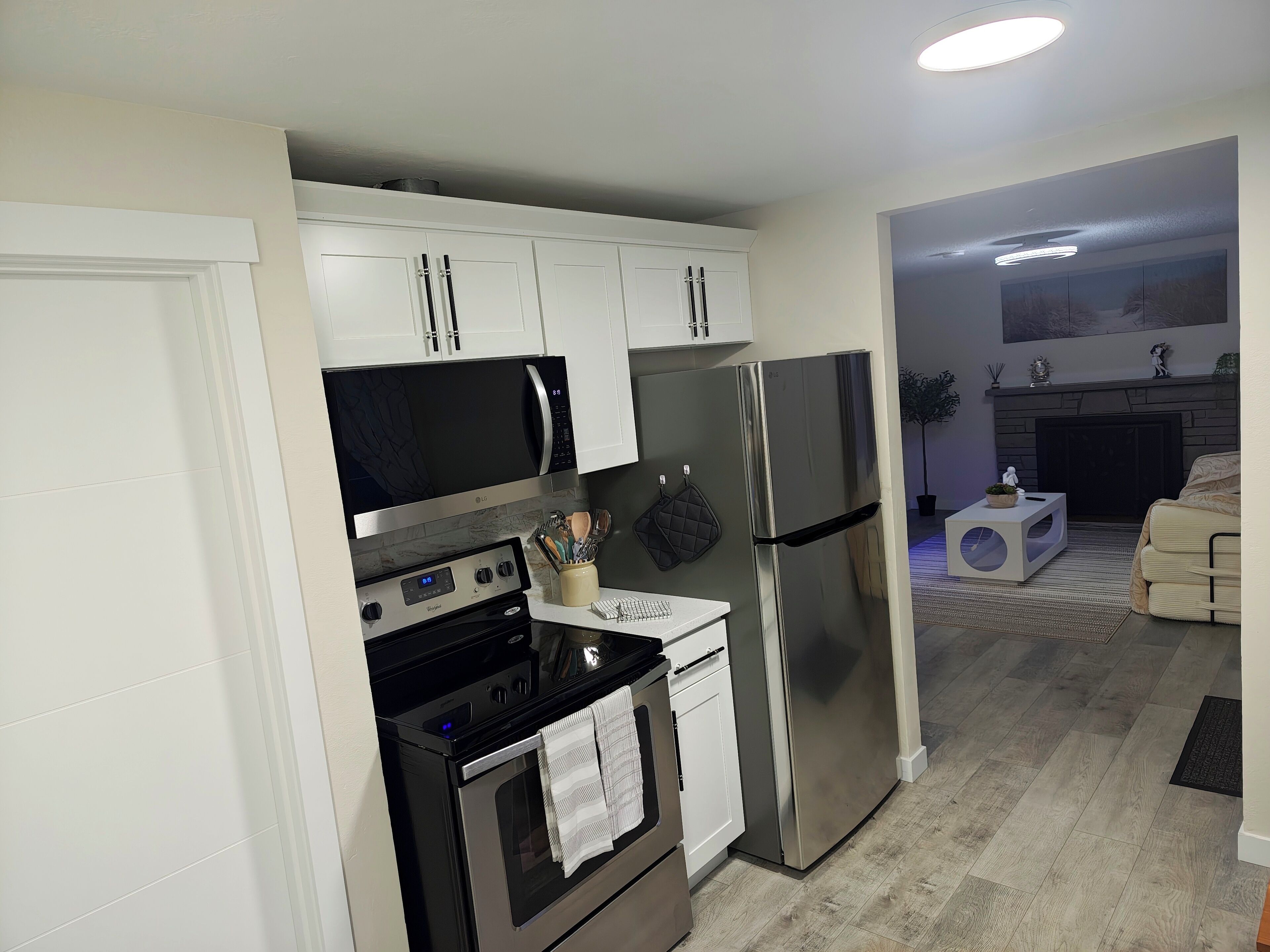 A modern kitchen with white cabinets, stainless steel appliances, and a marble backsplash.