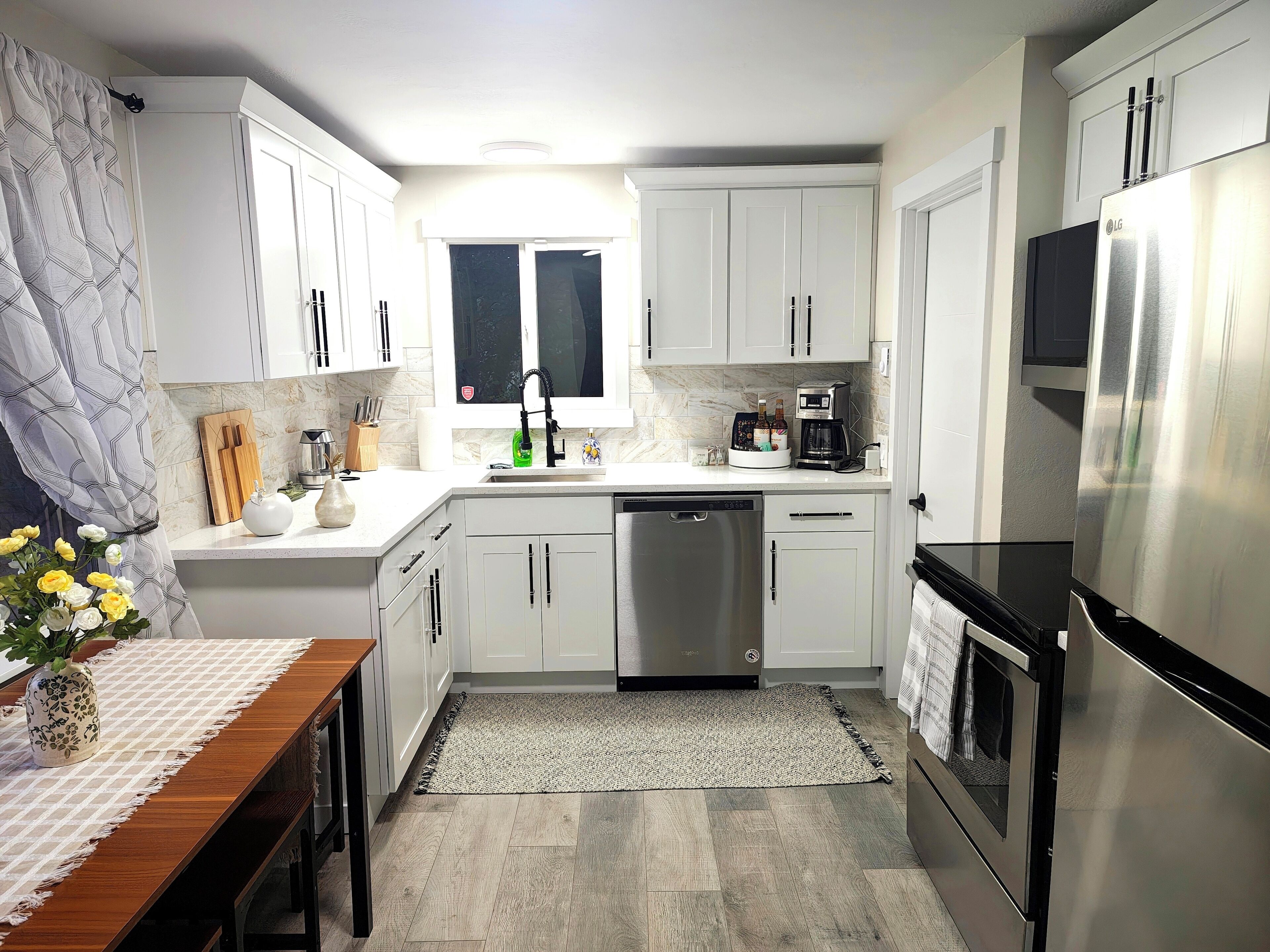 A modern kitchen with white cabinets, a stainless steel refrigerator, and a coffee maker.