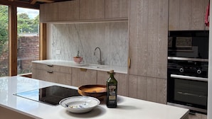 A modern kitchen with a skylight, wooden beams, a marble backsplash, and a built-in oven.