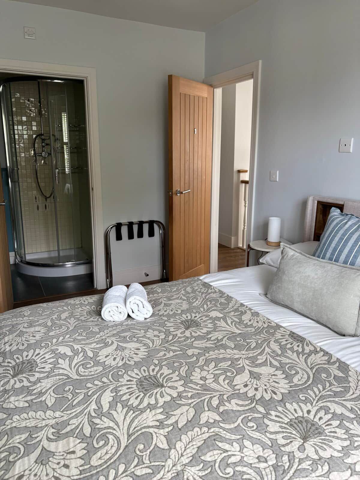 A hotel room with a bed, a shower, and a wooden door.
