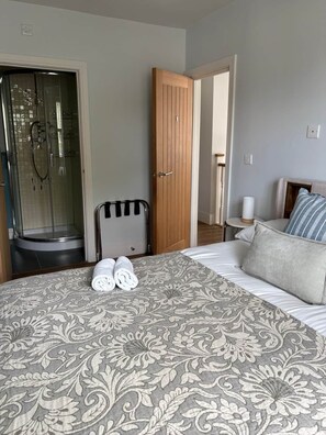 A hotel room with a bed, a shower, and a wooden door.