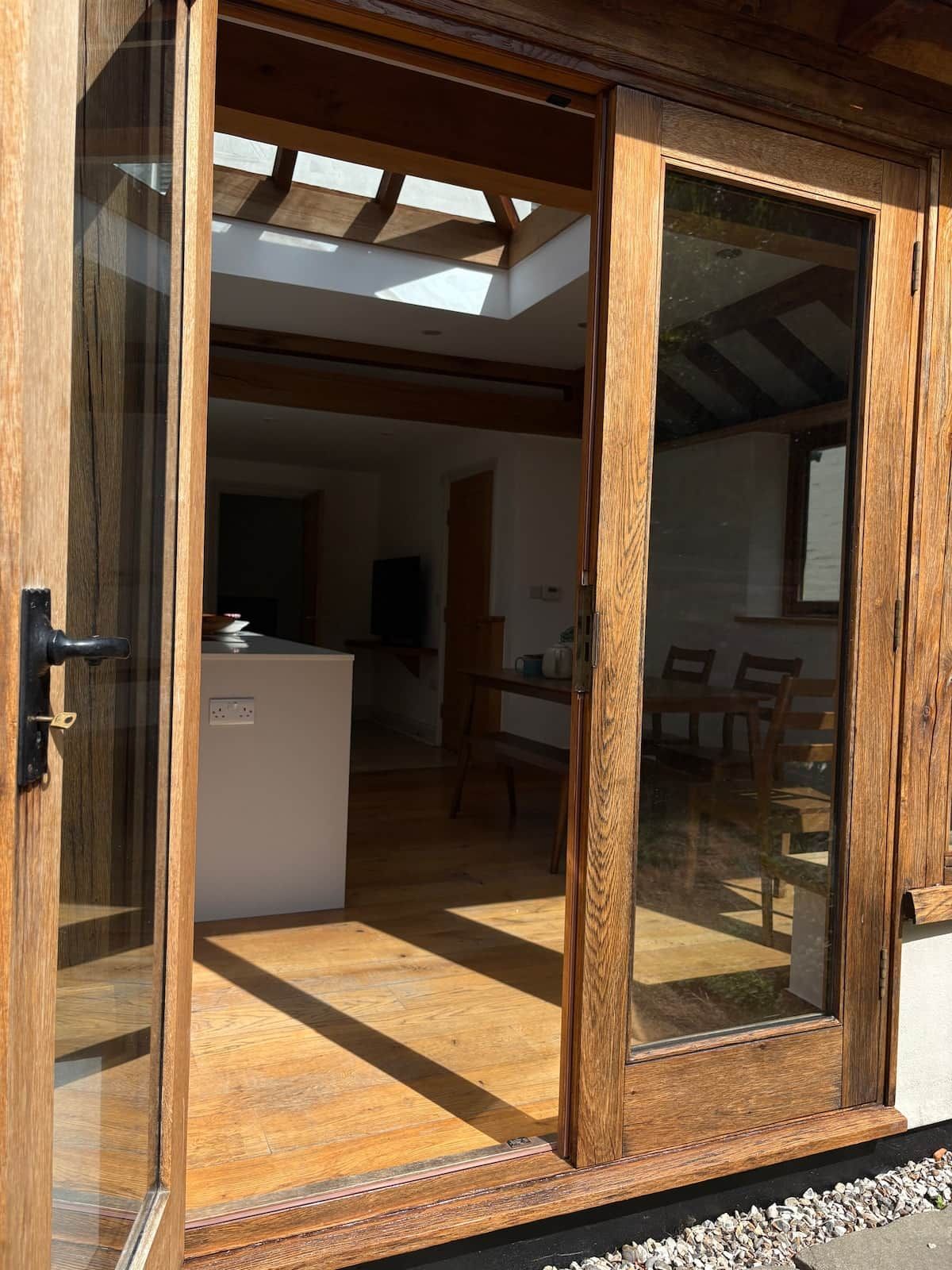 A wooden-framed sliding door leading to a room with a tiled floor, a kitchen area, and a dining table with chairs.