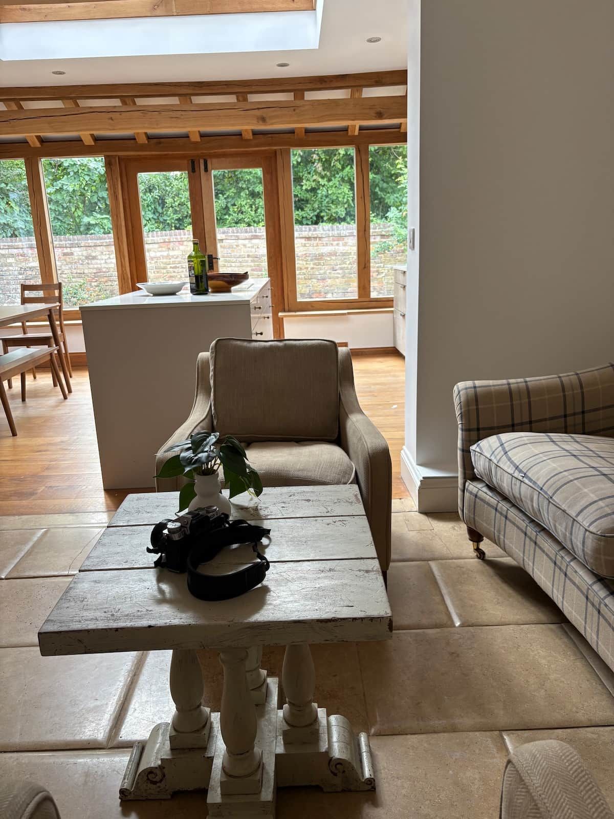 Un'ampia zona giorno con soffitto alto, un tavolo da pranzo, un divano e vista sull'esterno attraverso ampie finestre.