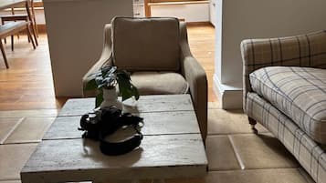 Un'ampia zona giorno con soffitto alto, un tavolo da pranzo, un divano e vista sull'esterno attraverso ampie finestre.