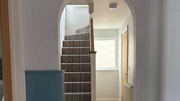 A hallway with a staircase, a radiator, and a pair of shoes on the floor.