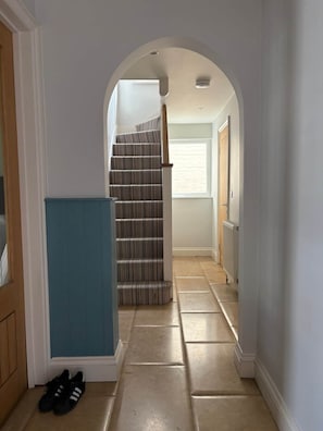 Ein Flur mit Treppe, Heizkörper und einem Paar Schuhe am Boden.