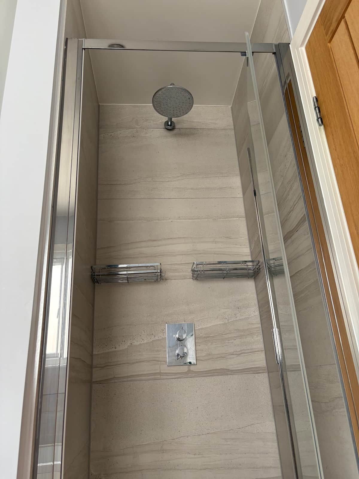A shower enclosure with a glass door, a showerhead, and a control panel.