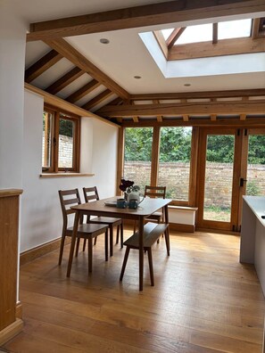 A dining area with a wooden table and chairs, a skylight, and a view of the outdoors.