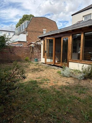 A residential property with a brick wall, a wooden door, and a small garden area.