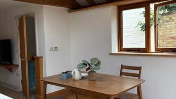 A dining area with a wooden table and benches, a window with a view, and a ceiling with wooden beams.