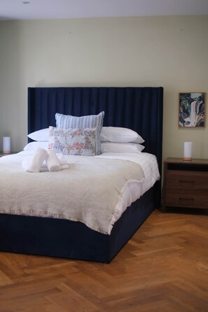 A neatly made bed with a dark headboard, white bedding, and decorative pillows.