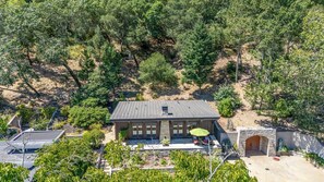 A house with a covered patio area, a stone archway, and a view of the surrounding forest.