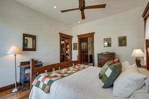A bedroom with a bed, a desk, a chair, a bookshelf, a dresser, and a ceiling fan.