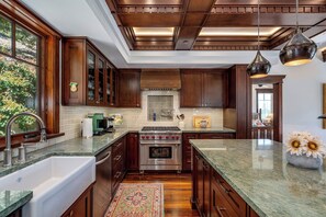 A modern kitchen with dark wood cabinets, a stainless steel stove, and a large island with a vase of sunflowers.