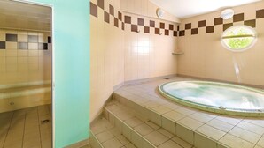 Un baño con bañera, paredes de azulejos y zona de ducha.