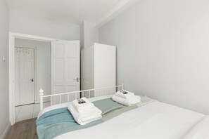 Ein Schlafzimmer mit einem Bett, einem weißen Kleiderschrank und einer Tür zu einem anderen Raum.