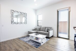 A modern living room with a grey sofa, a white coffee table, and a patterned rug.
