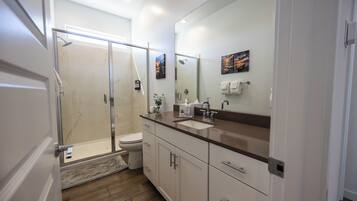 Une salle de bain moderne avec une douche à parois de verre, des toilettes, un lavabo et un grand miroir.