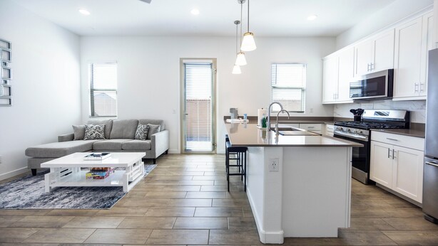 A modern kitchen with a central island, white cabinetry, and stainless steel appliances. - The Villa Suite @ Gilbert | Garage + Community Pool (Gilbert)