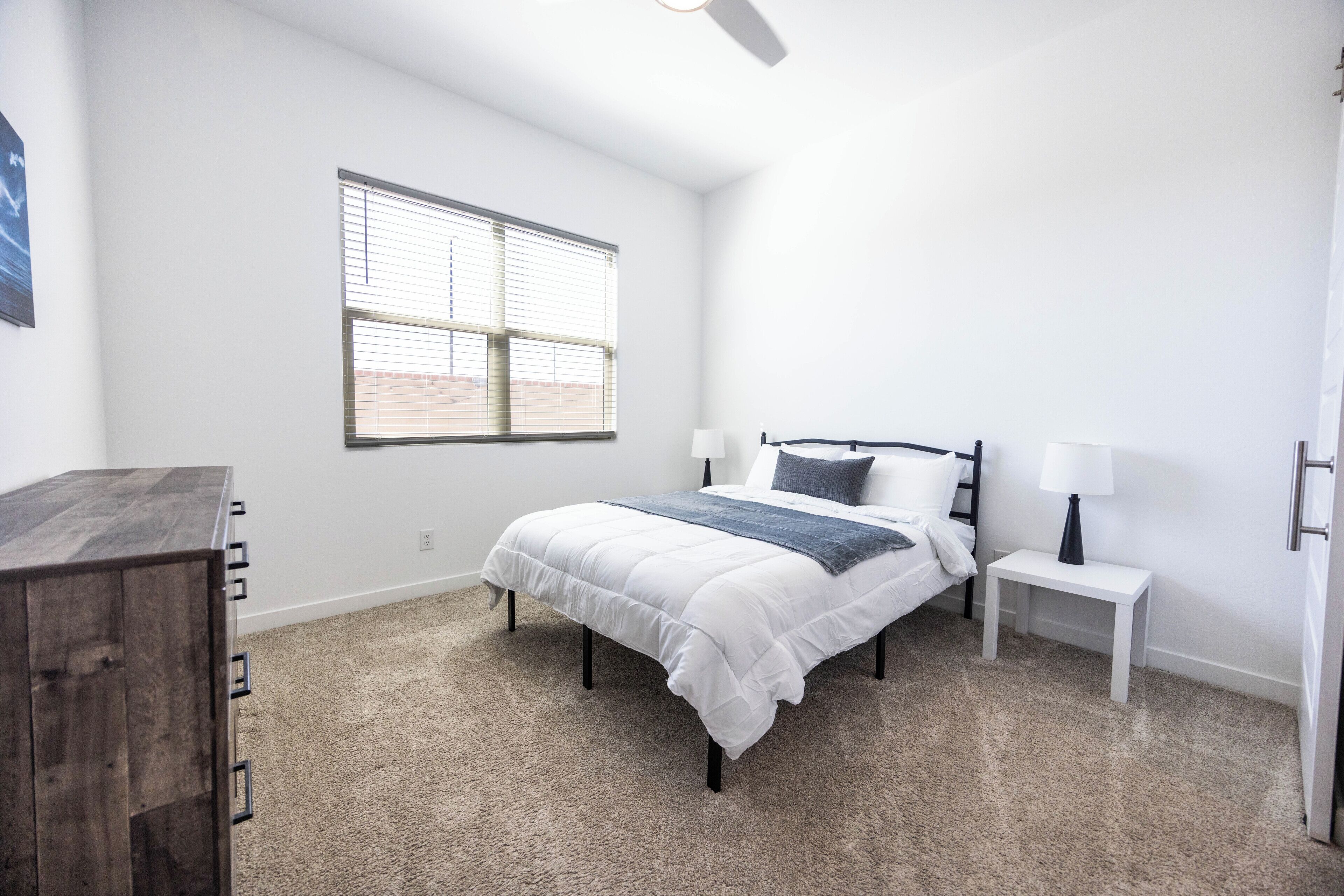 A bedroom with a bed, bedside tables, a ceiling fan, and a window.