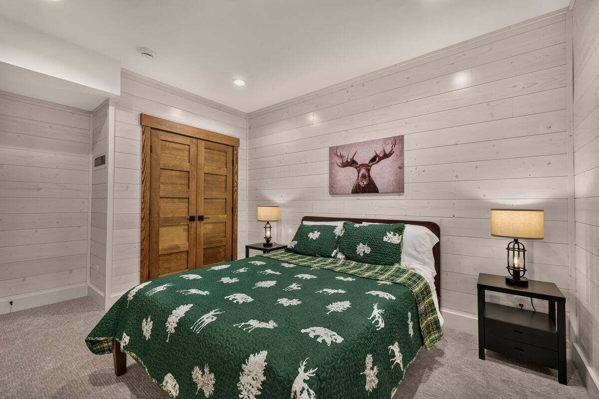 A bedroom with a bed, two nightstands, a wooden door, and a wall-mounted picture.