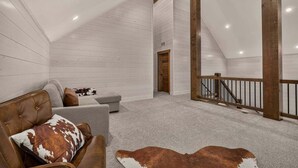 A loft-style room with a sloped ceiling, a staircase, and a view of the outdoors. - Pine and Sky Lodge+WiFi+AC+Hotub+30Min2Yellowstone (Island Park)