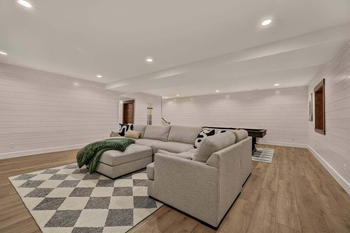 Uma sala de estar moderna com um sofá seccional, um tapete estampado e piso de madeira.