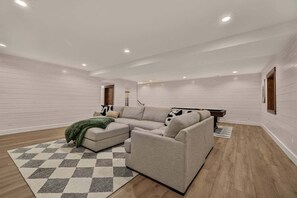 A modern living room with a sectional sofa, a patterned rug, and a wooden floor. - Pine and Sky Lodge+WiFi+AC+Hotub+30Min2Yellowstone (Island Park)