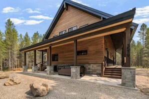 A modern log cabin with a covered porch, stone steps, and a stone fireplace. - Pine and Sky Lodge+WiFi+AC+Hotub+30Min2Yellowstone (Island Park)